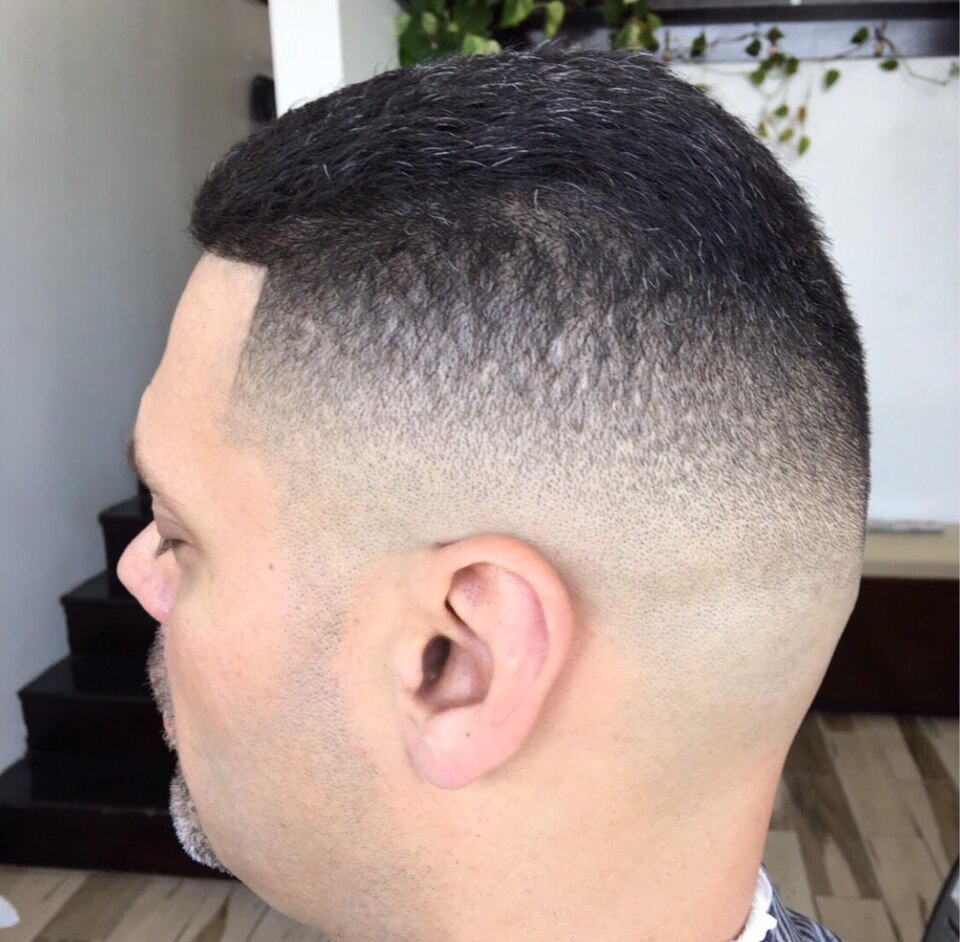 Dégradé homme net sur cheveux poivre et sel, vu de profil en sortie de coupe