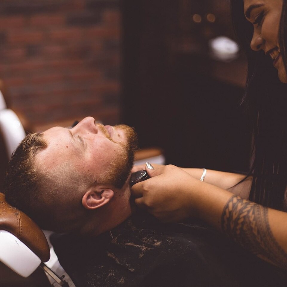 Barbier taillant les contours de barbe d'un client au salon